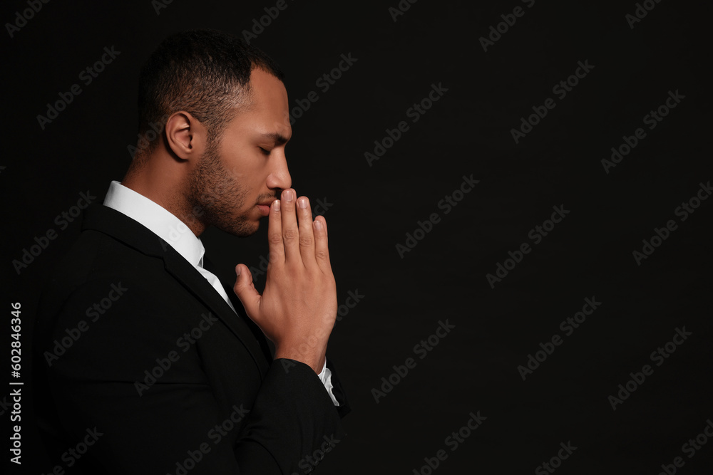 African American man with clasped hands praying to God on black background. Space for text African American man with clasped hands praying to God on black background. Space for text