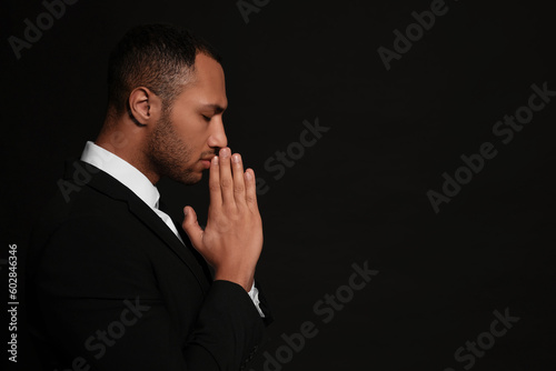 Фотография African American man with clasped hands praying to God on black background