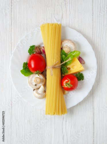 Pasta spaghetti, cheese, vegetables and spices on a white wooden table