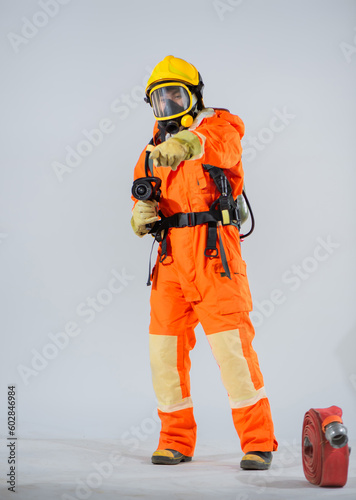 Vertical picture of firefighter standing and pointing finger to the camera while a fire hose on the floor on white background.