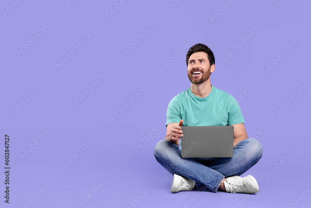 Happy man with laptop on purple background. Space for text Happy man with laptop on purple background. Space for text