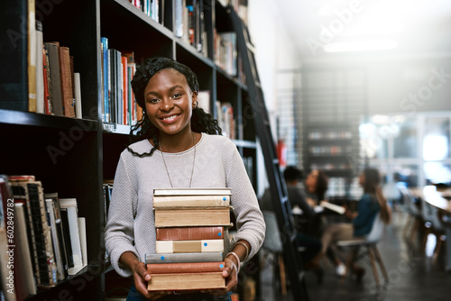 Portrait, education and black woman with books, library and university with a smile, bookshelf and studying. Face, female person or happy student with research, literature and learning with knowledge
