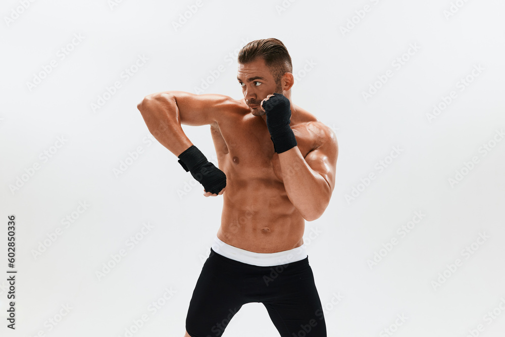 Man athletic bodybuilder poses in boxing gloves with nude torso abs in full-length background, boxing and martial arts. Advertising, sports, active lifestyle, light, competition, challenge concept. Man athletic bodybuilder poses in boxing gloves with nude torso abs in full-length background, boxing and martial arts. Advertising, sports, active lifestyle, light, competition, challenge concept.