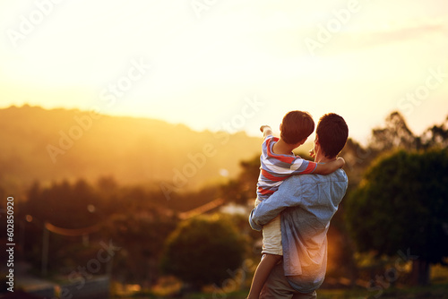 Father, child and pointing to sunset in nature for travel, holiday or weekend getaway outdoors. Back of dad holding kid enjoying the future, sunrise or horizon for family bonding on mockup space photo