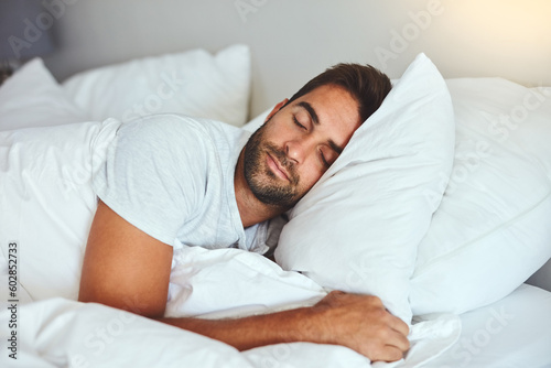 Man, sleeping and bed in morning rest for healthy wellness, peace and quiet on comfort pillow at home. Tired or exhausted male person asleep or dreaming on peaceful holiday or weekend in the bedroom photo