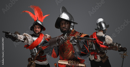 Portrait of multiethnic group of three conquistadors with steel armors and flintlock rifles.