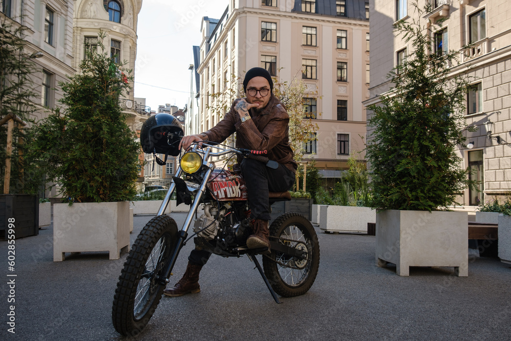 Shot of trendy hipster driving old fashioned vintage motorbike outdoors.