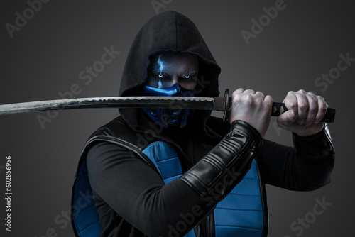 Portrait of Ice assassin dressed in costume with hood posing with katana.