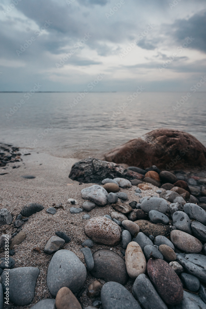 Close up of beach rocks on shore of Lake Ontario on cloudy evening.