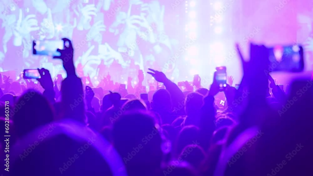 Large crowd of fans enjoying live performance in front of stage and recording with smartphones