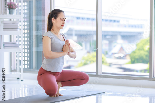 Asian beautiful healthy fit slim sexy female sporty athlete model in sportswear and leggings standing doing eagle posture on yoga mat in class