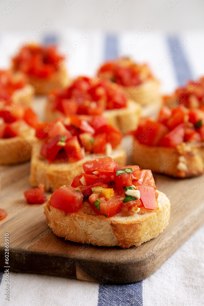 Homemade Italian Bruschetta Appetizer with Fresh Basil and Juicy Tomatoes on a Wooden Board, side view. Close-up.