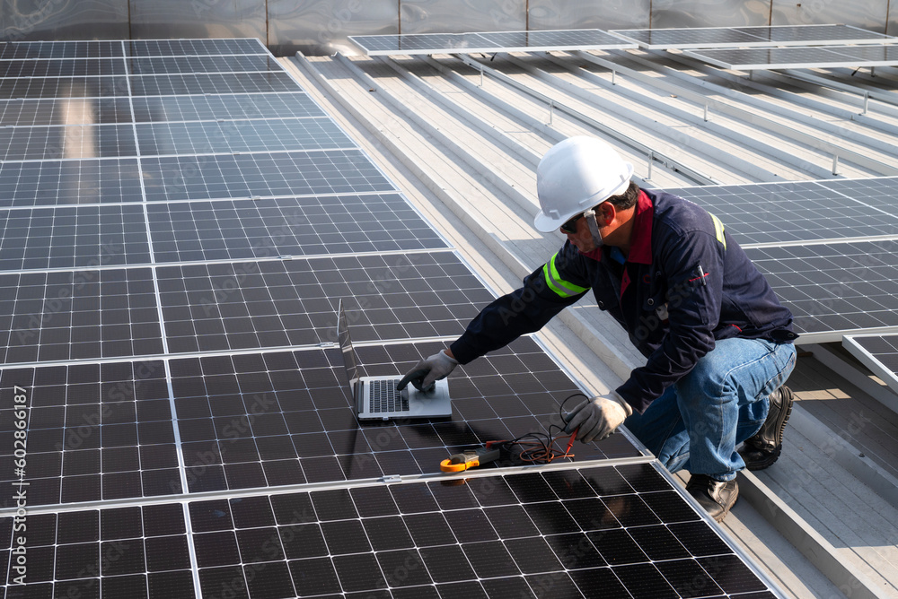 technician inspecting solar panels on factory roof Check and maintain the solar panel roof A team of technicians installing solar panels on the roof of a high-rise building