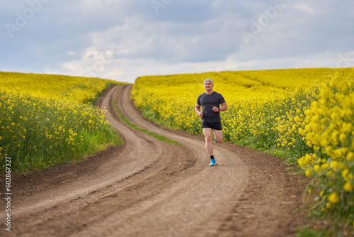 Distance runner running on a road through canola field