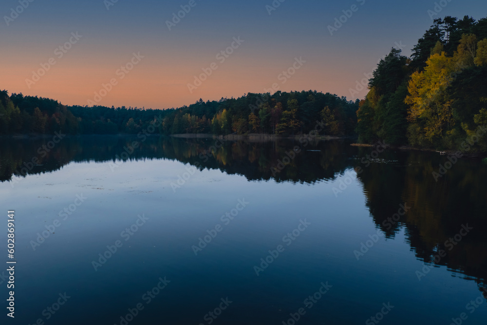 Stunningly beautiful lake in the golden autumn season. Magical multi-color reflection with light ripples on the surface of the water fall evening. Autumn scenery Colorful vibrant autumn forest with