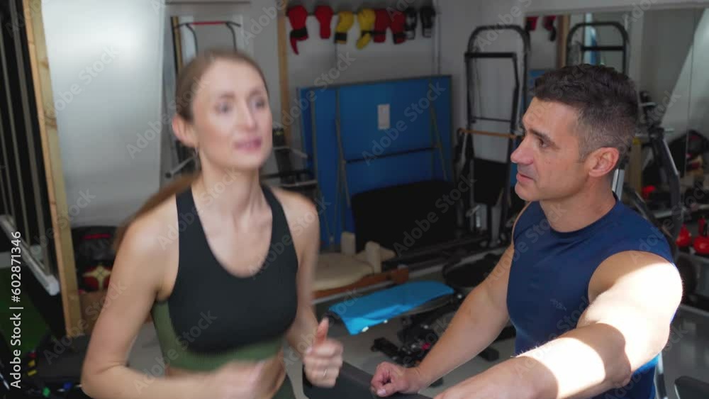 Personal trainer inspires a woman to run on the treadmill during an intense workout at the gym Personal trainer inspires a woman to run on the treadmill during an intense workout at the gym