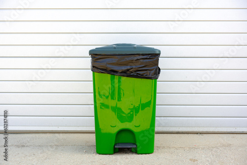 Green plastic garbage container standing in the street
