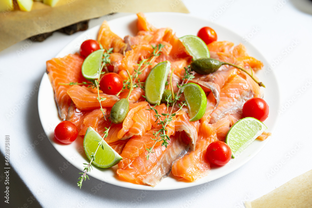 Salmon carpaccio with tomatoes, olives and lime on white plate Salmon carpaccio with tomatoes, olives and lime on white plate