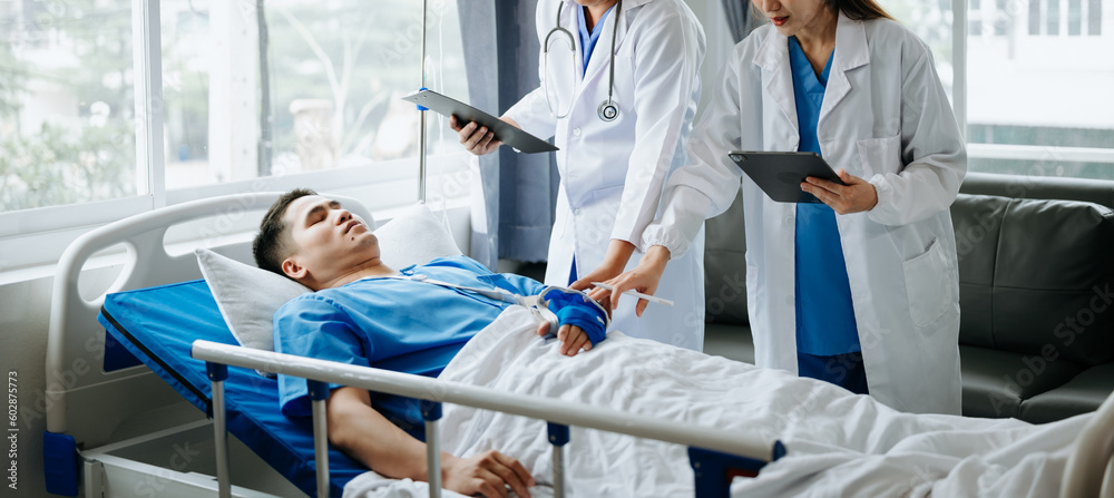 Two doctors talking to a patient lying in his bed  with receiving saline solution in hospital .