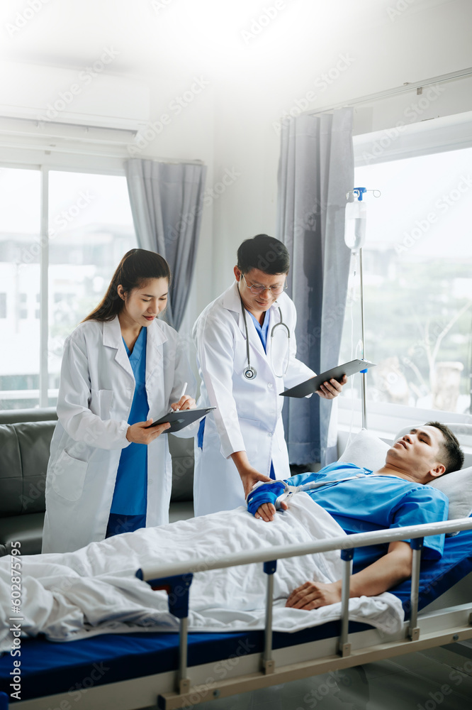 Obraz premium Two doctors talking to a patient lying in his bed with receiving saline solution in hospital .