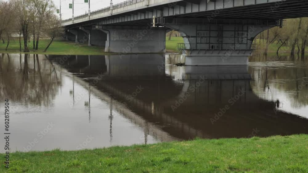 A road bridge over a river. The muddy Dnieper River flows under the bridge. Brown water in the river after the spring flood. Cityscape A road bridge over a river. The muddy Dnieper River flows under the bridge. Brown water in the river after the spring flood. Cityscape