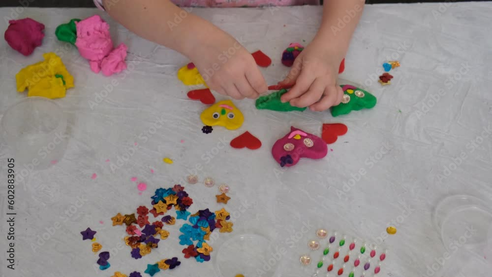 Child making funny crafts  clay, plasticine. Cute hearts  as gift for Mothers day, Fathers day, Birthday or Valentines day . Arts  crafts concept.