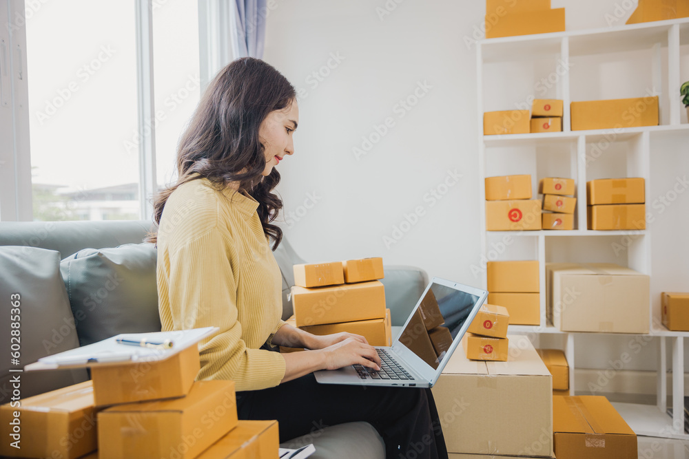Freelance Female SME Small Business Entrepreneur Working at Office BOX, Tablet and Laptop Online, Marketing, Packaging, Shipping, Ecommerce Concept.. Freelance Female SME Small Business Entrepreneur Working at Office BOX, Tablet and Laptop Online, Marketing, Packaging, Shipping, Ecommerce Concept..
