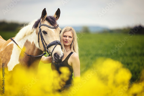 horse and young girl in portraits behind yellow flowers isolated behind blurred foreground and background.