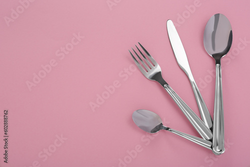 Stylish cutlery set on pink background, flat lay. Space for text