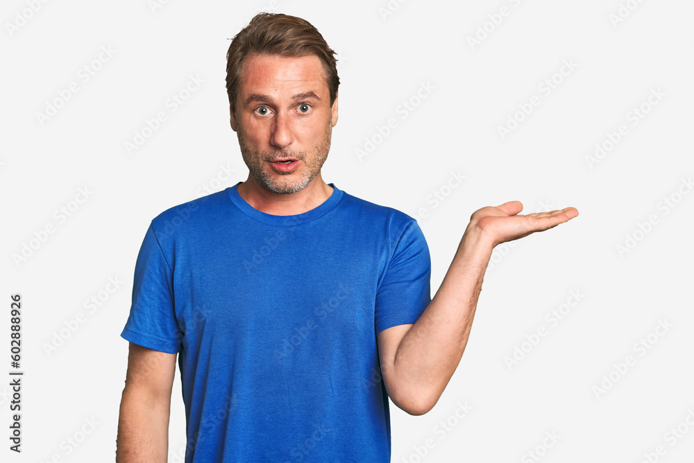 A middle-aged man isolated impressed holding copy space on palm. A middle-aged man isolated impressed holding copy space on palm.
