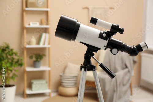 Tripod with modern telescope in stylish room, closeup