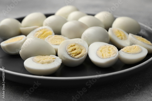 Plate with many peeled hard boiled quail eggs on grey table, closeup