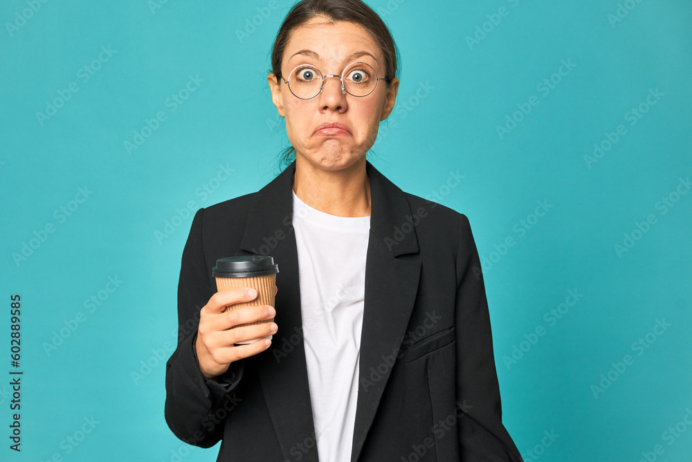 A young caucasian business woman holds a takeaway coffee shrugs shoulders and open eyes confused. A young caucasian business woman holds a takeaway coffee shrugs shoulders and open eyes confused.