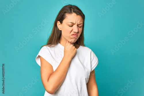 A young caucasian woman isolated suffers pain in throat due a virus or infection.