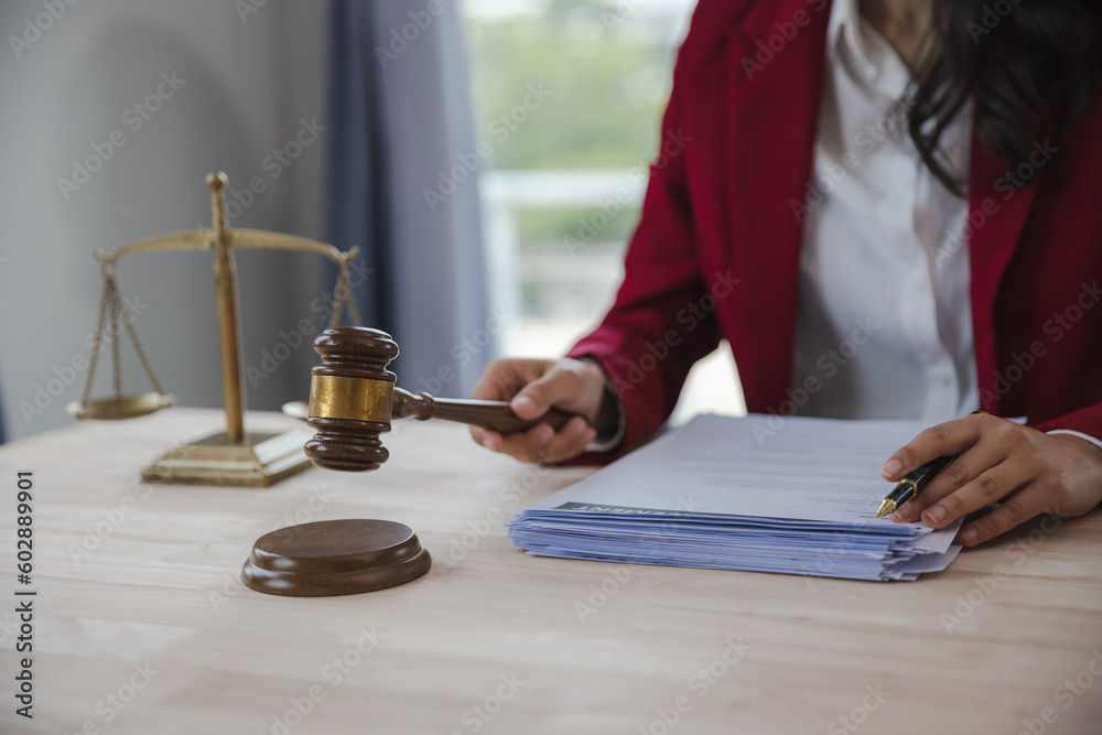 Businesswoman and lawyer discussing contract documents with brass scales on wooden table in office. Law, legal services, advice, justice and real estate concept. Businesswoman and lawyer discussing contract documents with brass scales on wooden table in office. Law, legal services, advice, justice and real estate concept.