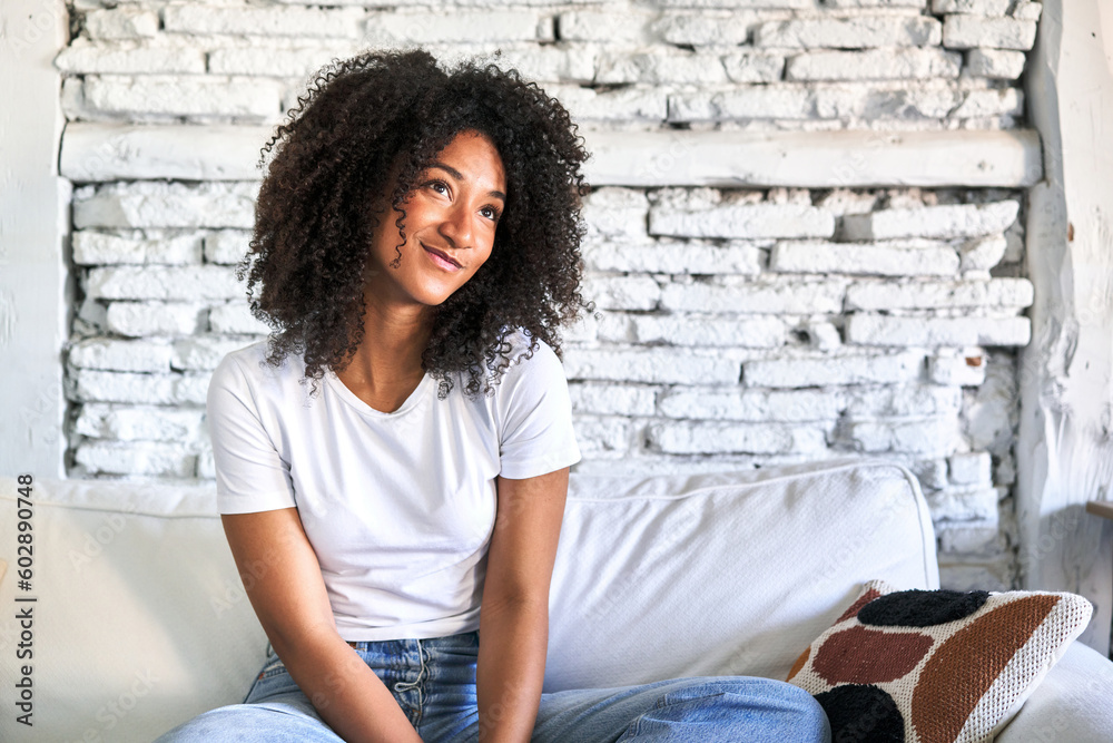 A young african american woman sitting on her sofa dreaming of achieving goals and purposes A young african american woman sitting on her sofa dreaming of achieving goals and purposes