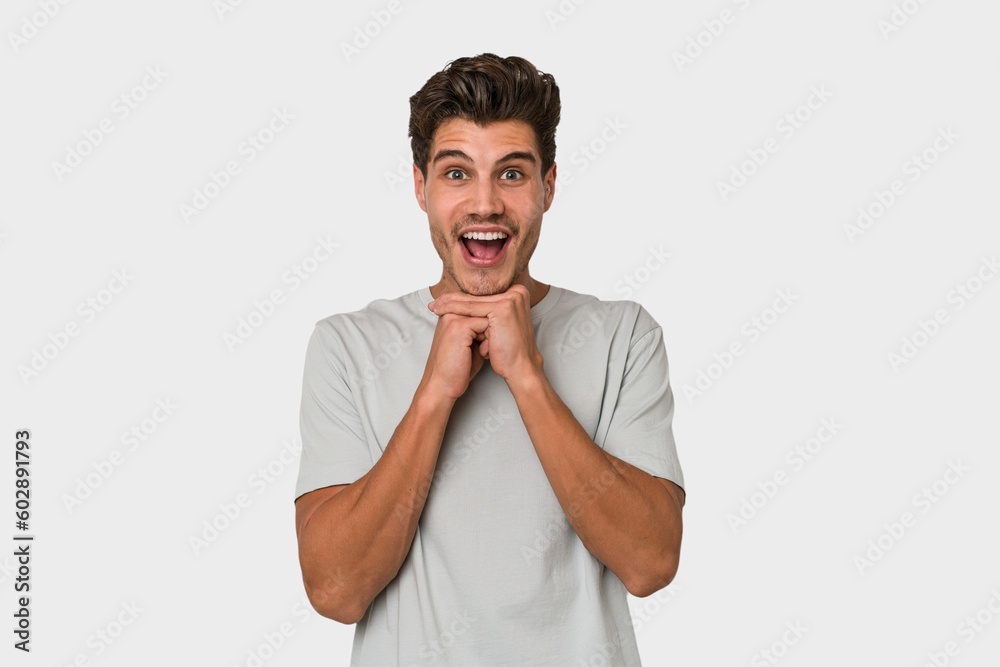 Young handsome caucasian man isolated on white background praying for luck, amazed and opening mouth looking to front. Young handsome caucasian man isolated on white background praying for luck, amazed and opening mouth looking to front.