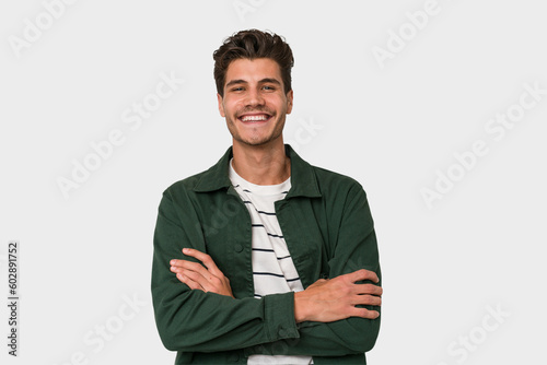 Young handsome caucasian man isolated on white background who feels confident, crossing arms with determination. photo