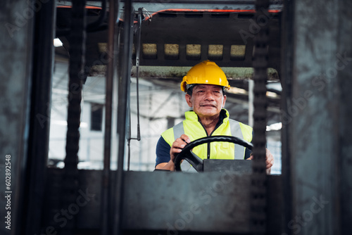 Portrait of industrial worker driving a forklift in the factory. Engineer is working and maintaining in the warehouse.