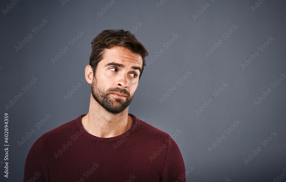 Doubt, thinking and face of unsure man in studio with worry, uncertain and thoughtful on gray background. Confused, mockup space and isolated male person skeptical for decision, choice and question
