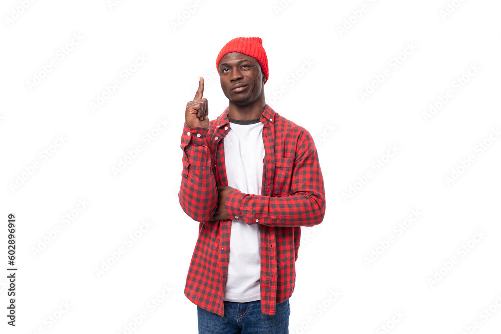 smart cute 30s black american man dressed in red shirt and cap communicates idea on white studio background with copy space smart cute 30s black american man dressed in red shirt and cap communicates idea on white studio background with copy space