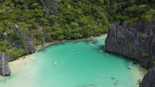 People kayak and swim in tropical emerald Cadlao Lagoon, El Nido, Aerial.
Idyllic tropical turquoise Ubugon Cove amid jagged karst rock formations, part of island hopping Tour D, Philippines photo