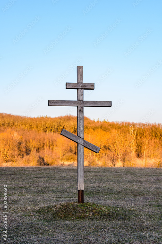 Old wooden cross on a meadow against sky