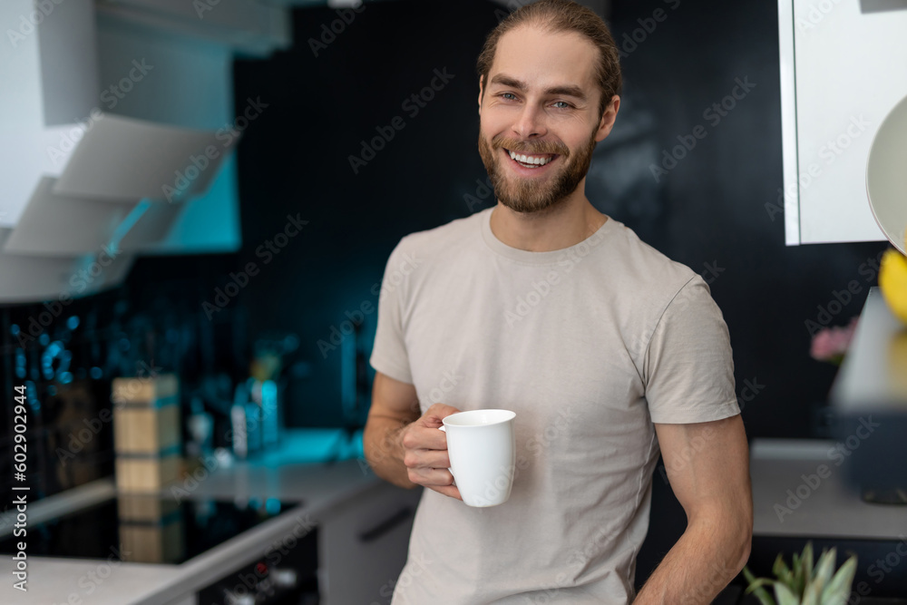 Man enjoying morning coffee in kitchen with modern interior, drinking fresh warm beverage at home. Man enjoying morning coffee in kitchen with modern interior, drinking fresh warm beverage at home.