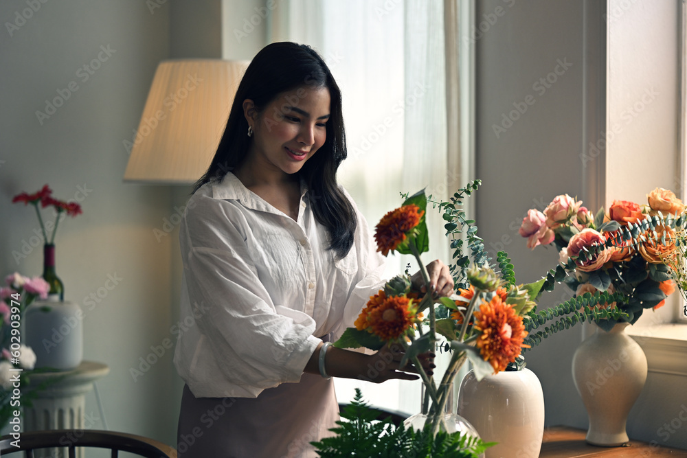 Attractive Asian woman enjoys arranging fresh flowers