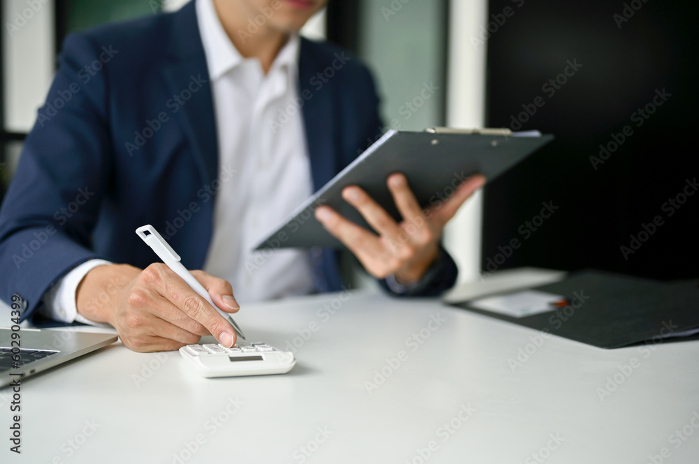 Close-up image of a businessman using a calculator to calculate his business sales Close-up image of a businessman using a calculator to calculate his business sales