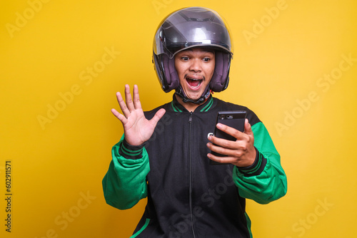 Asian online taxi driver motorbike man shocked and surprised while checking his smartphone isolated over yellow background