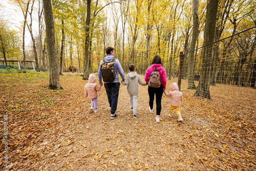 Fototapeta Naklejka Na Ścianę i Meble -  Back of family with kids on a walk in autumn forest.