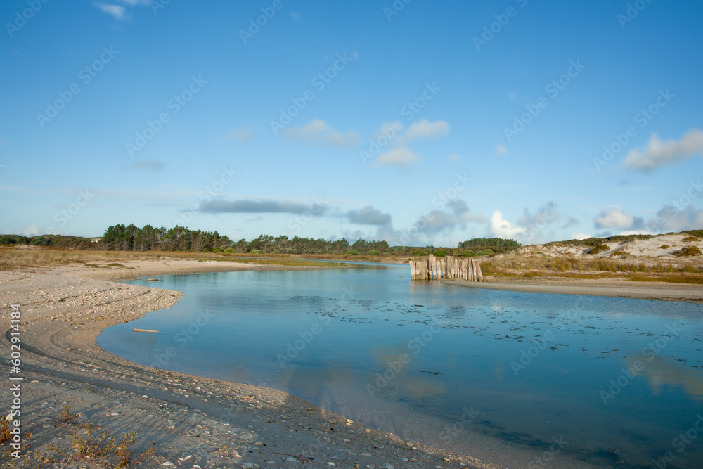 Stream running through sand dunes to beach