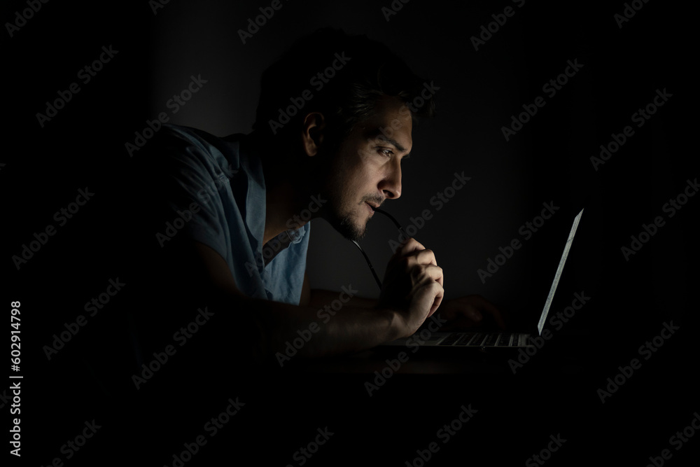 Side view of young handsome man working on laptop at night. Work from home concept Side view of young handsome man working on laptop at night. Work from home concept